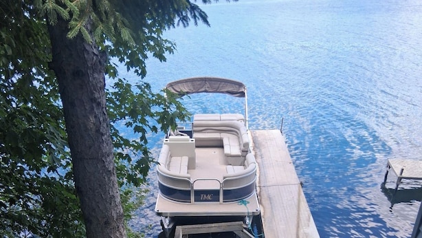 A boat docked at a wooden pier with a staircase leading down to the water. - Rustic recently updated 3-bedroom cabin with AC on Upper Turtle Lake. (Turtle Lake)