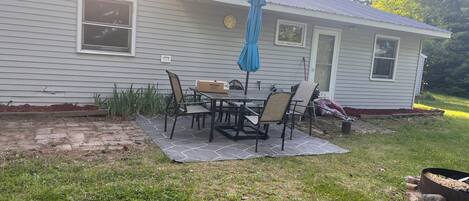 Una casa con un patio que incluye una mesa, sillas, un reloj y un buzón.