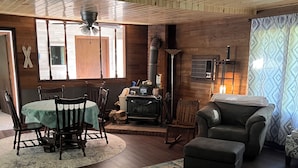 A cozy living room with a wooden ceiling, a fireplace, a dining table with chairs, and a sofa. - Rustic recently updated 3-bedroom cabin with AC on Upper Turtle Lake. (Turtle Lake)