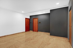 A hallway with two wooden doors, a grey wall, and a tiled floor. - Suite Room Health Visakhapatnam Nebo (Visakhapatnam)