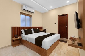 A modern hotel room with a bed, bedside tables, an air conditioning unit, a television, and a wooden door. - Suite Room Health Visakhapatnam Nebo (Visakhapatnam)