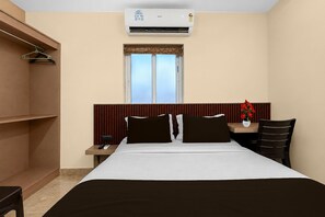 Une chambre d’hôtel équipée d’un lit, d’un bureau, d’une chaise, d’une fenêtre et d’un appareil de climatisation.