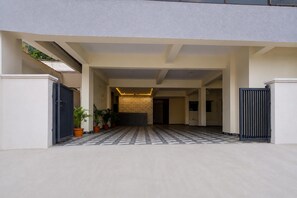 A covered outdoor area with a tiled floor, potted plants, and a wall with a textured pattern. - Suite Room Health Visakhapatnam Nebo (Visakhapatnam)
