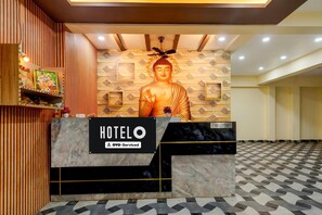 A hotel reception desk with a large Buddha statue in the background. - Suite Room Health Visakhapatnam Nebo (Visakhapatnam)