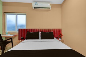 Ein Hotelzimmer mit einem Bett, einem Schreibtisch, einem Stuhl, einem Fenster und einer Klimaanlage.