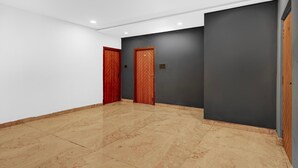Un pasillo con dos puertas de madera, una pared gris y un suelo de baldosas.