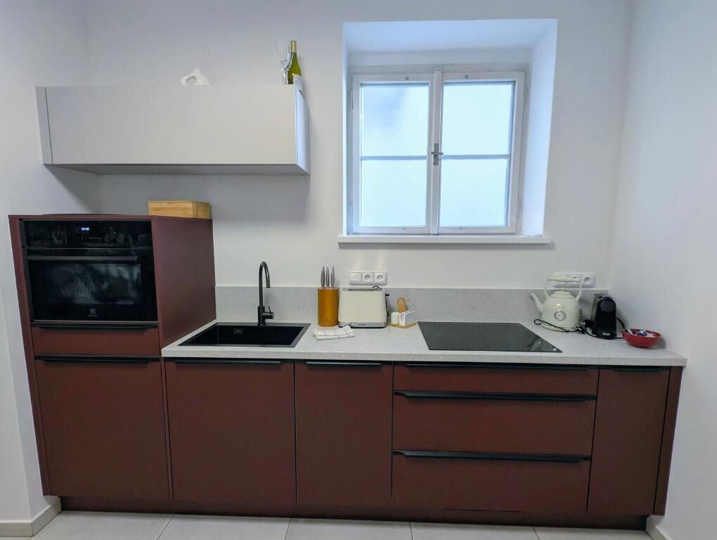Eine Küche mit Einbauofen, Spüle, Fenster und einer Arbeitsplatte mit Toaster.