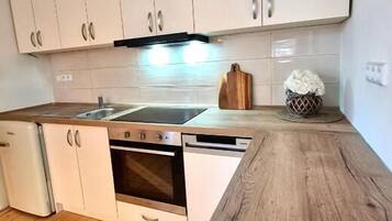 A kitchen with white cabinets, a wooden countertop, a dishwasher, and an oven.