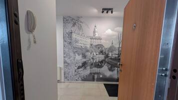 A hallway with a wooden door, a wall-mounted telephone, and a large black-and-white mural of a castle and river.