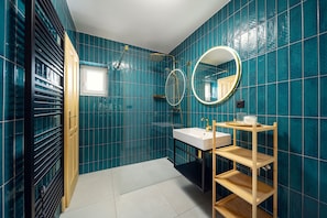 Un baño con azulejos verde mar, un lavabo blanco, un espejo y una ducha.