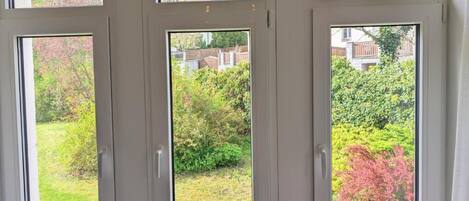 A set of three windows with a view of a garden and a house.