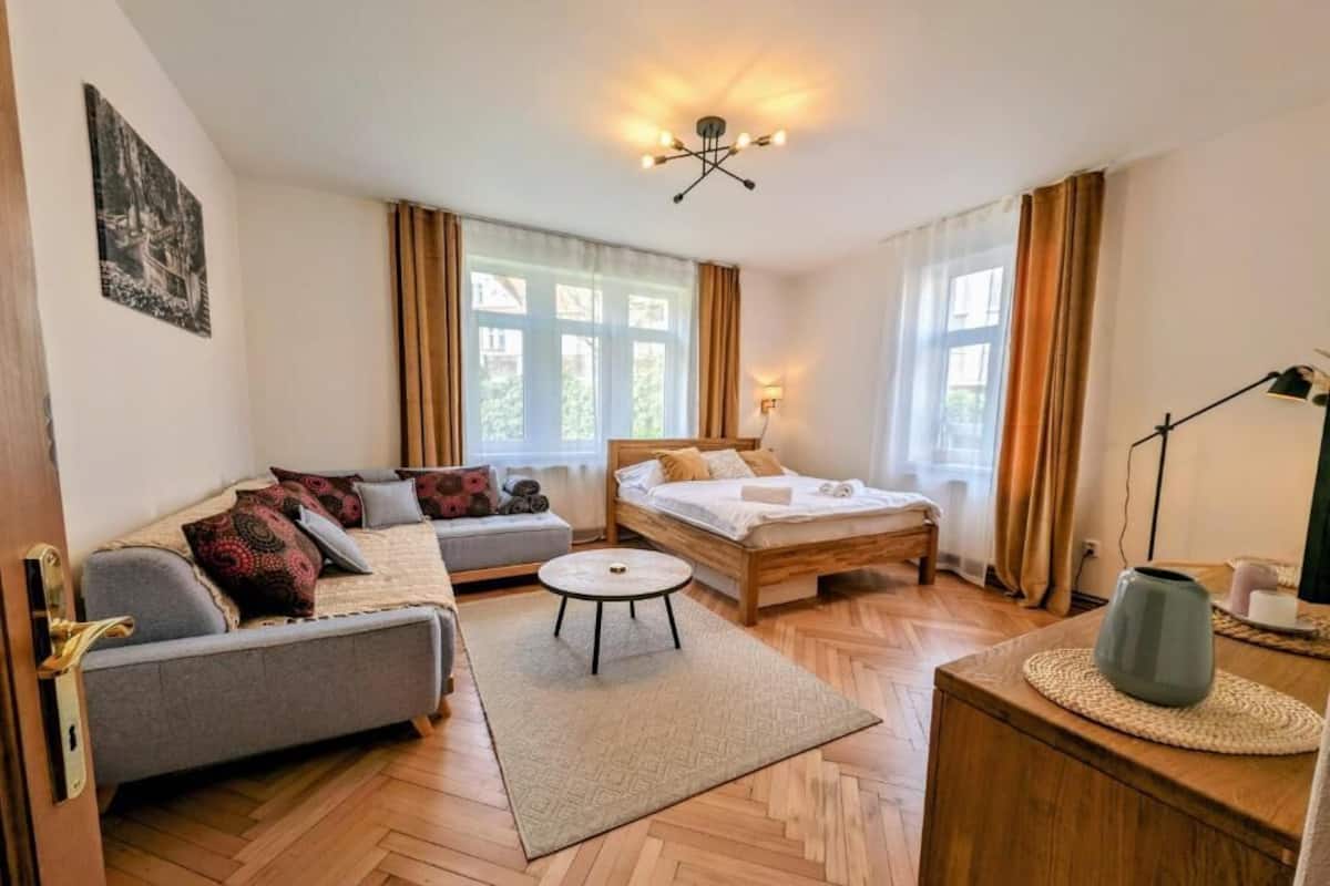 A room with a bed, sofa, and a small round table.