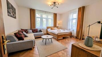 A room with a bed, sofa, and a small round table.