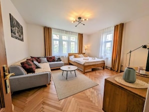 A room with a bed, sofa, and a small round table.