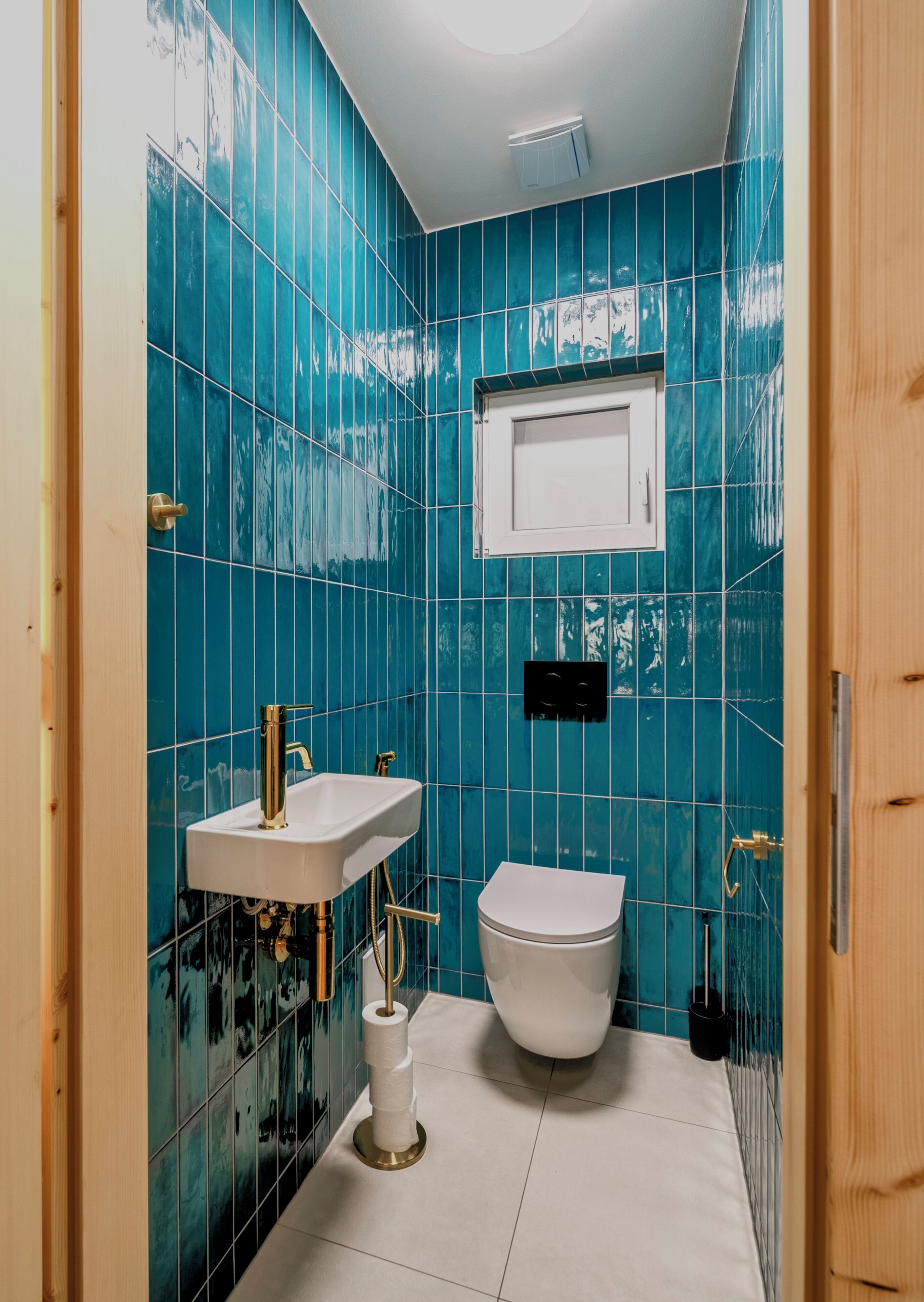 Un baño con azulejos azules, un lavabo blanco y un inodoro.