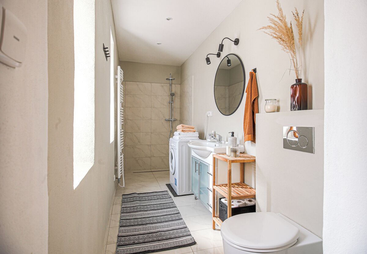 A modern bathroom with a shower, toilet, sink, and a mirror.