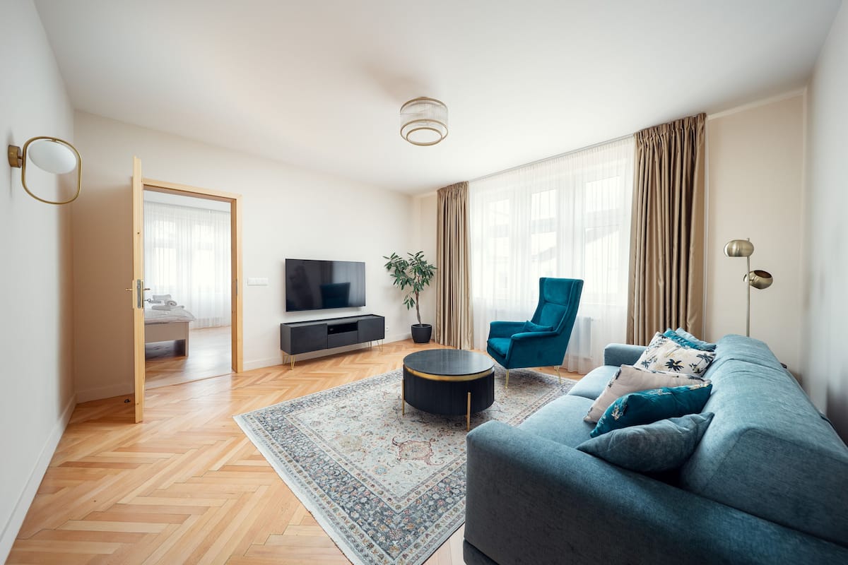 Un salon moderne avec un canapé, un téléviseur, une plante et un fauteuil bleu.
