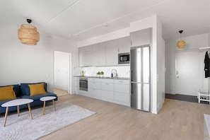A modern kitchen with white cabinets, a stainless steel refrigerator, and a microwave.