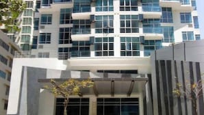 Un edificio de varios pisos con un diseño arquitectónico moderno, que cuenta con una serie de balcones y ventanas amplias.