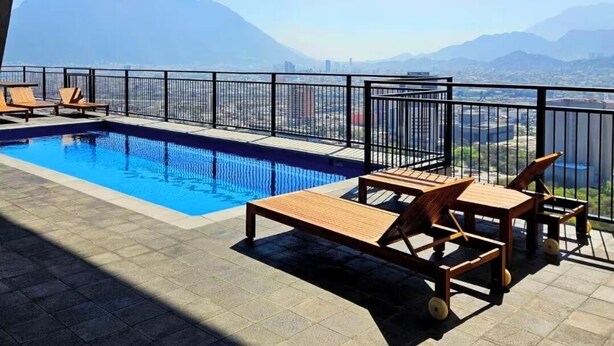 Ein Pool auf dem Dach mit Holzliegen und Blick auf die Berge.