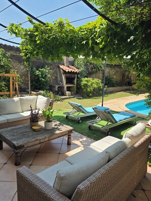A patio with wicker furniture, a pool, and a stone wall. - Winegrower's house 500m² - Swimming pool - Baillargues - 12 pers. (Baillargues)