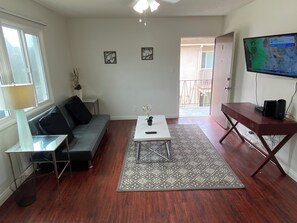 Una sala de estar con sofá, mesa de centro, televisor y un tapete estampado.