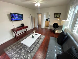 A living room with a flat-screen TV, a sofa, a coffee table, and a patterned rug. - Charming 2-bedroom apartment near Venice, SMC (Santa Monica)