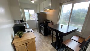 Una cocina compacta con comedor, estufa, refrigerador y ventana con vistas.