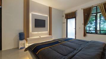 Een slaapkamer met een bed, een wandgemonteerde televisie, een waterdispenser en een raam met gordijnen.