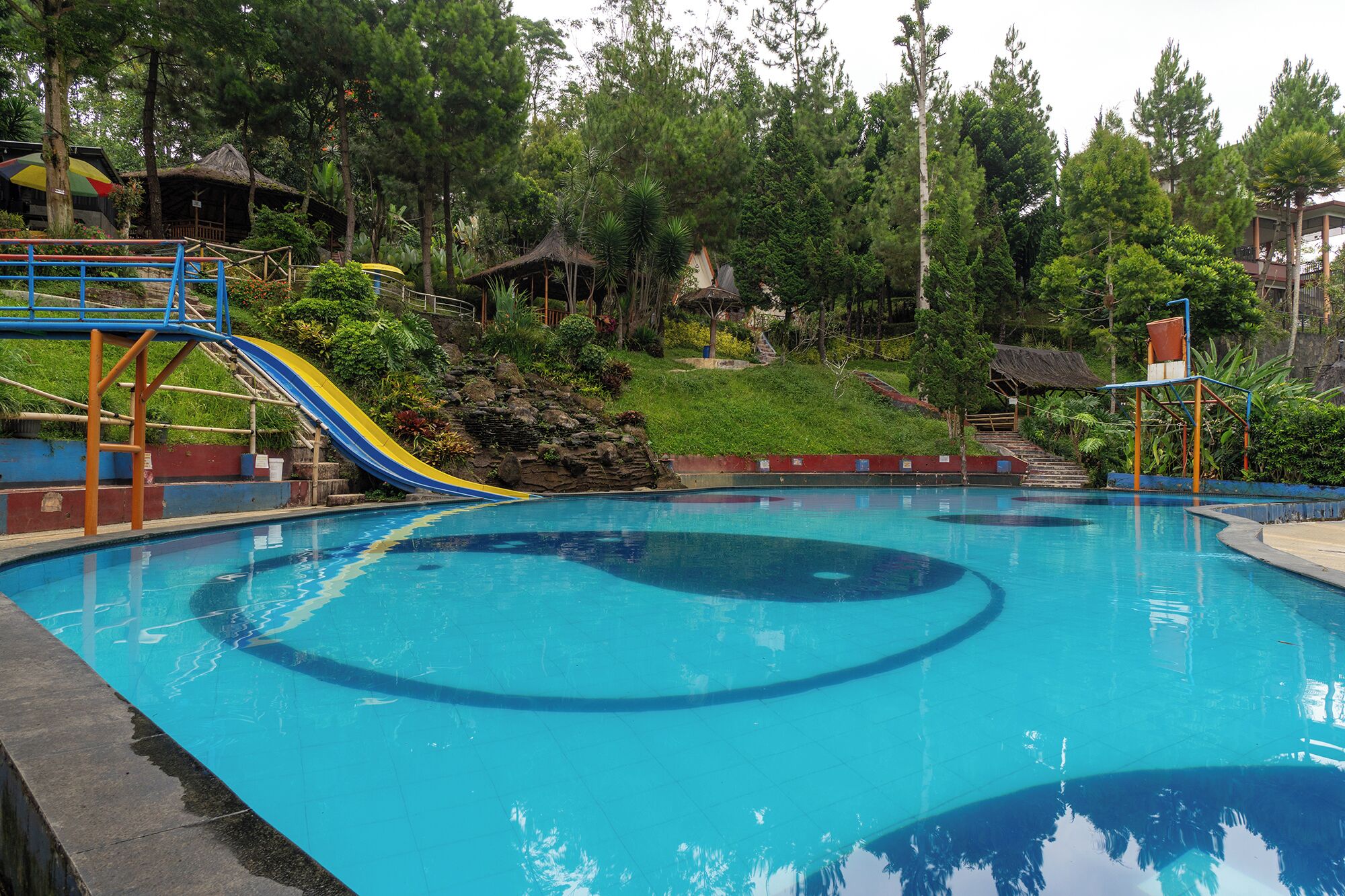 A swimming pool with a slide and a small waterfall feature.