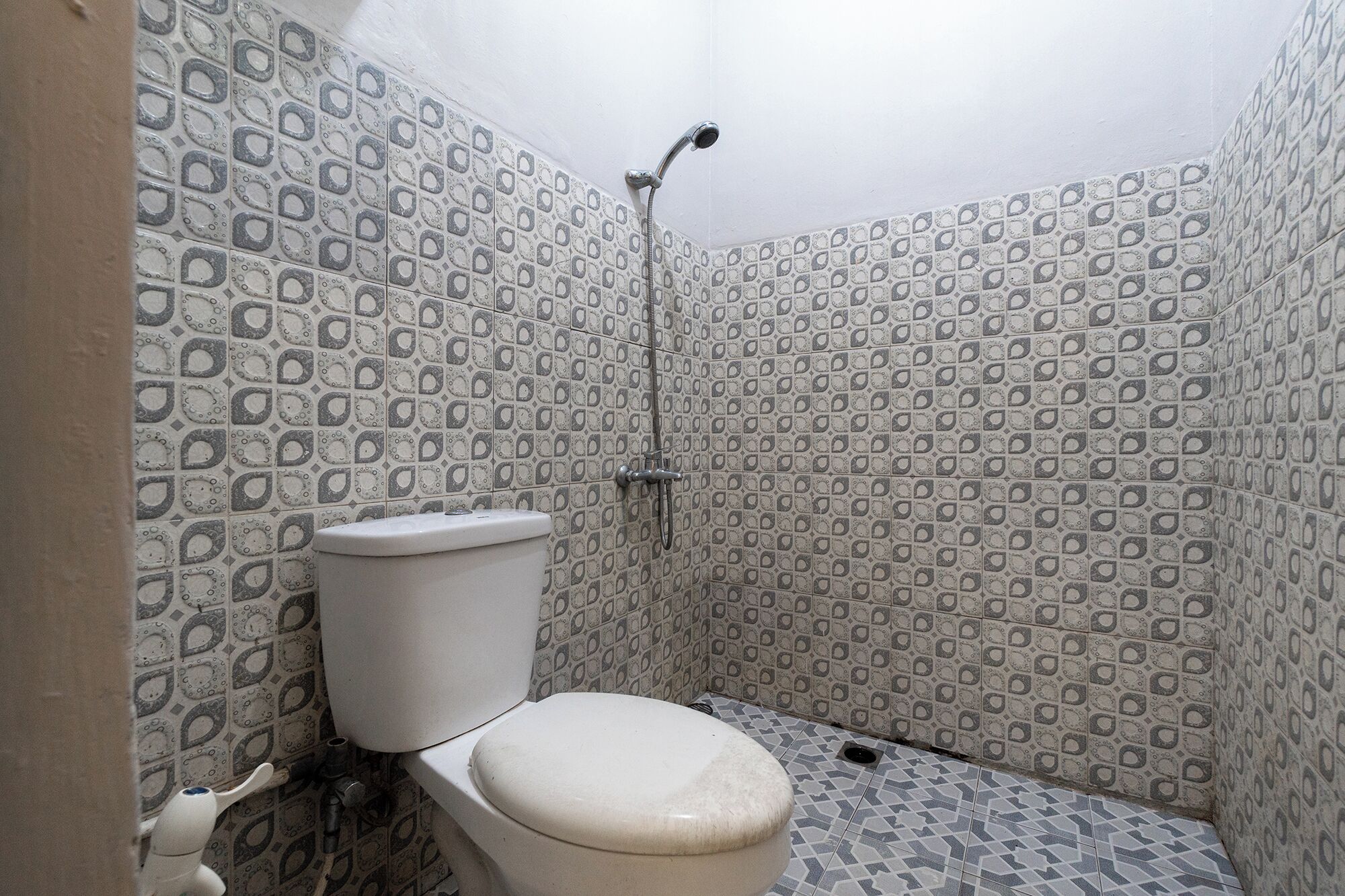 A bathroom with patterned tiles, a toilet, and a shower.