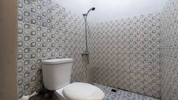 A bathroom with patterned tiles, a toilet, and a shower.