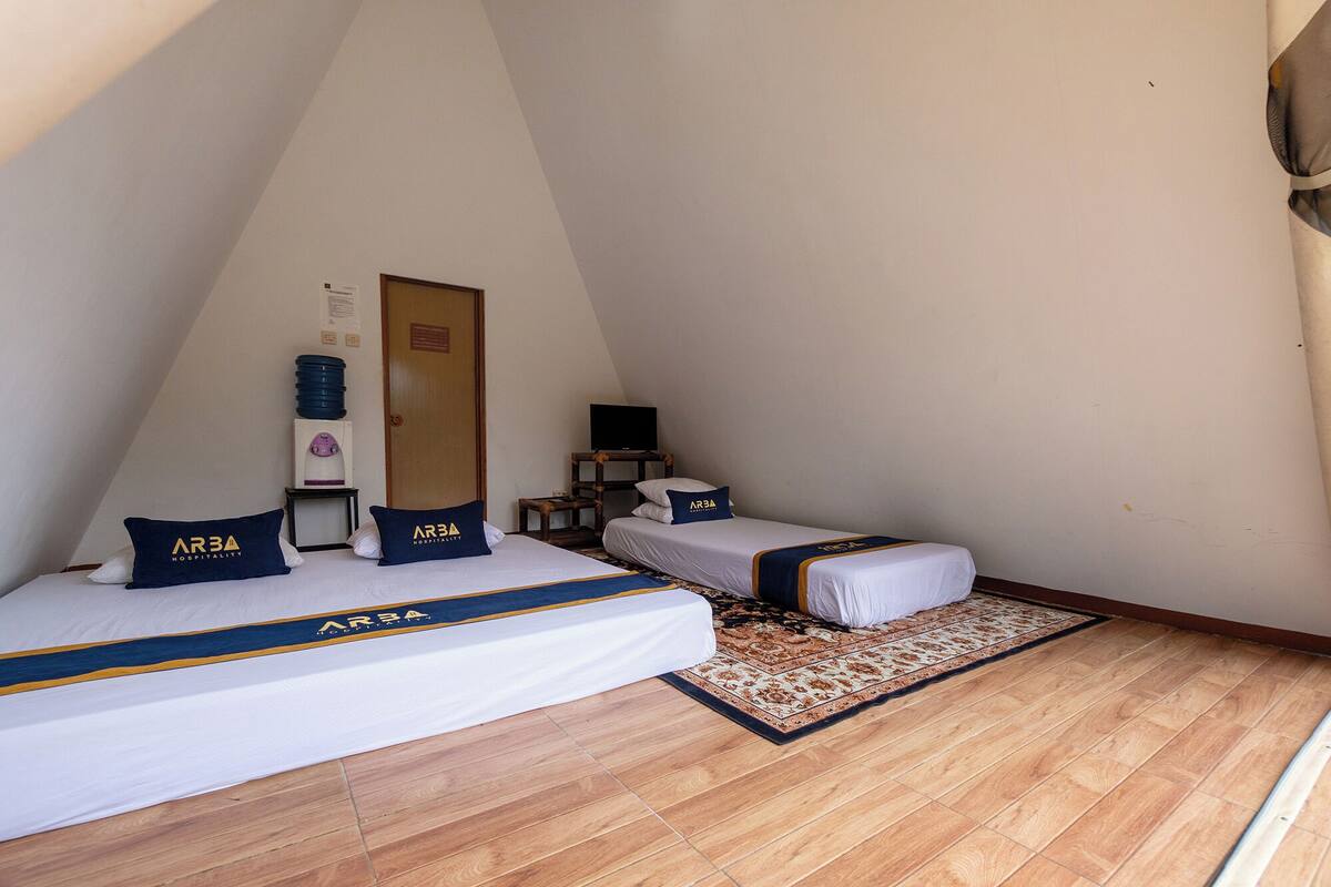 A small, triangular room with a bed, a desk, and a television.