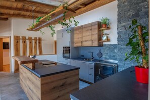 Eine moderne Küche mit Holzschnitzereien, einer Kochinsel und hängenden Pflanzen.