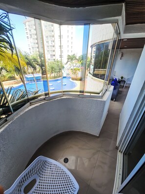 Un balcón con vistas a una piscina y edificios circundantes.