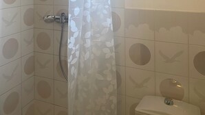 A bathroom with a shower, toilet, and a framed artwork on the wall.