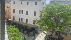 A multi-story building with a courtyard featuring outdoor seating and barrels.