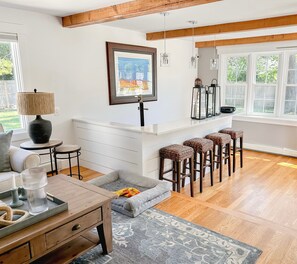 A modern living room with a wooden ceiling, a dining area with bar stools, a grey sofa, and a kitchen island. - 1 mile from Main Street and 1.5 miles to Falmouth Heights Beach. (Falmouth)