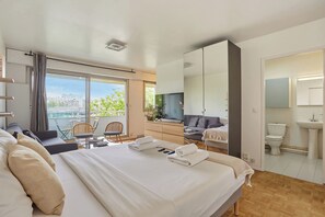 A hotel room with a bed, a desk, a television, a balcony with a view, and a bathroom. - Charming Studio Bercy Village/accor Arena (Paris)