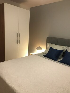 Ein Schlafzimmer mit einem Bett, einem Nachttisch, einer Lampe und einem Kleiderschrank.