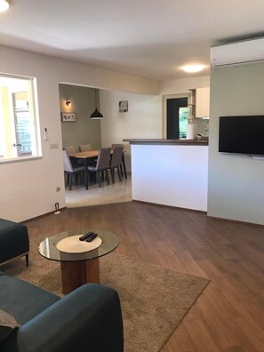 Ein modernes Wohnzimmer mit Glastisch, einer Couch und einem Essbereich mit Stühlen und Tisch.