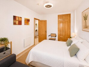 Ein Schlafzimmer mit einem Bett, einem Sessel, einem Schreibtisch und einem Kleiderschrank.