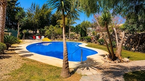 A swimming pool surrounded by tropical plants and a stone wall. - Casa Ideal | Valle del Este, Vera (Vera)