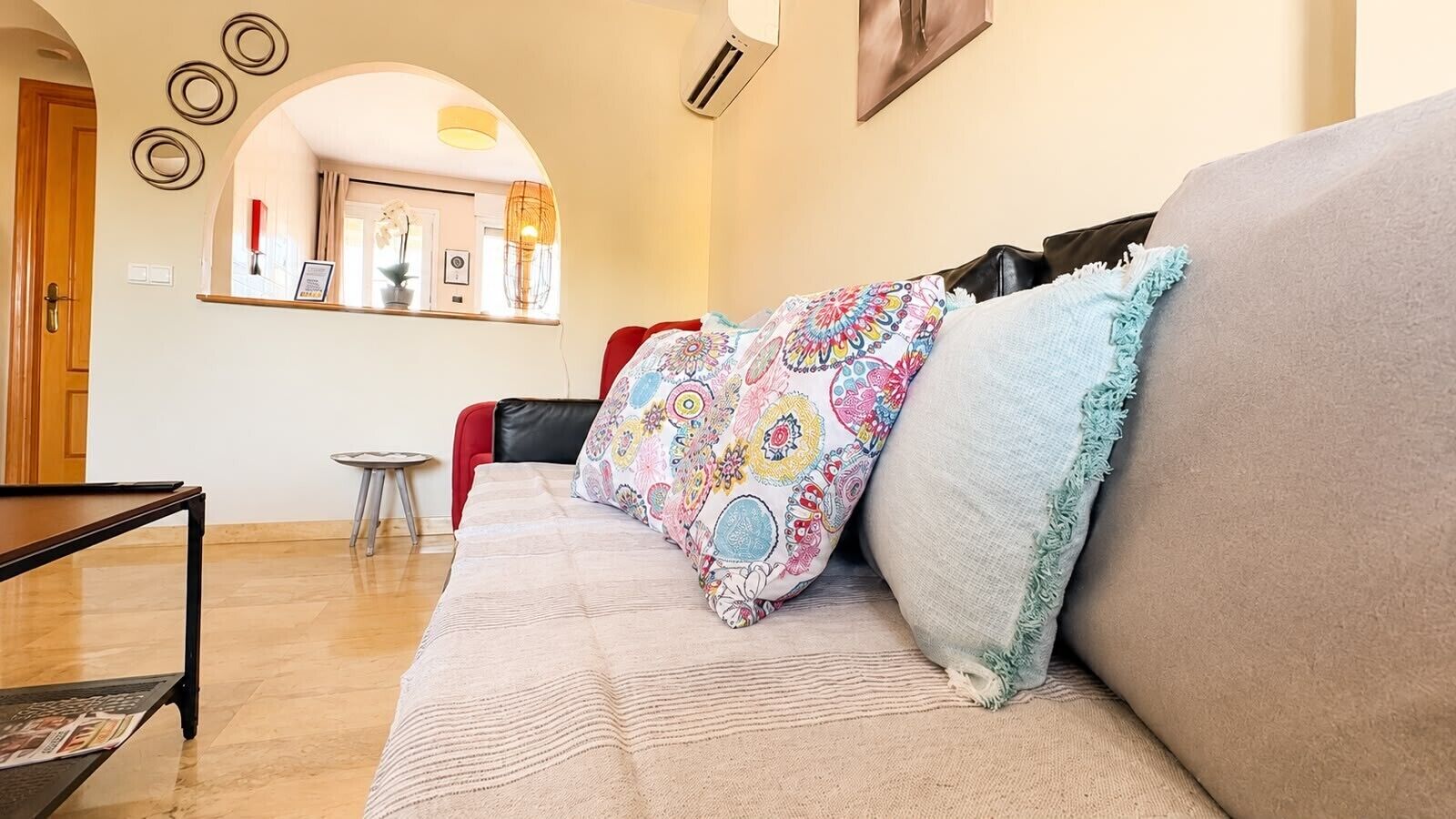 Uma sala de estar com sofá, uma mesinha, um espelho e uma porta.