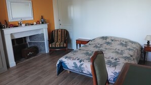 Ein Zimmer mit Bett, Sessel, Kamin und einer Tür.