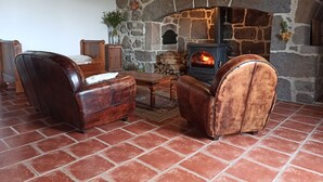 Ein gemütliches Zimmer mit Kamin aus Stein, Ledersesseln und einem Holztisch.