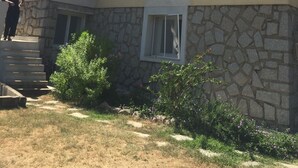 Un bâtiment à deux étages, avec une base en pierre et une partie supérieure jaune, doté de nombreuses fenêtres avec volets, d’une petite fenêtre à cadre blanc et d’un escalier menant à l’entrée.