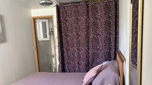 Une chambre à coucher avec un lit, un miroir, une lampe et une porte.