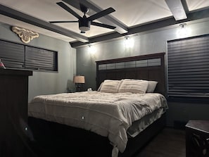 Ein Schlafzimmer mit Bett, Deckenventilator, Lampe und Wandleuchte.