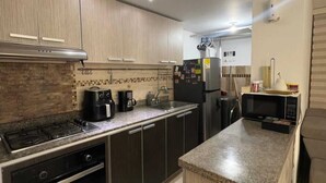 Eine moderne Küche mit Gasherd, Backofen, Mikrowelle, Kühlschrank und Kaffeemaschine.